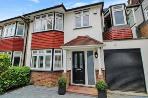 een huis met een zwarte deur en een garage bij Stunning Caterham 4 bedroom home in Kenley