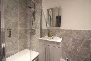 een badkamer met douche, wastafel en spiegel bij Stunning Caterham 4 bedroom home in Kenley