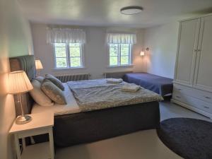 a bedroom with a bed and a nightstand and two windows at Påryds Bed & Breakfast in Påryd