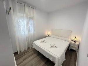 ein weißes Schlafzimmer mit einem Bett und einem Fenster in der Unterkunft Apartamento Empul Barrosa Beach in Novo Sancti Petri + 4 Fotos