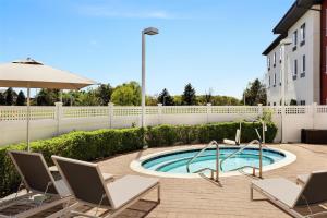 a swimming pool with chairs and an umbrella at Hilton Garden Inn Riverhead in Riverhead
