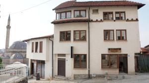 a tall white building with windows and a mosque at Hattuşa Hostel in Prizren