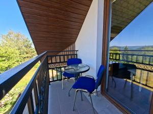a balcony of a house with blue chairs and a table at Bieszczadzki Dom Gościnny w Werlasie in Werlas