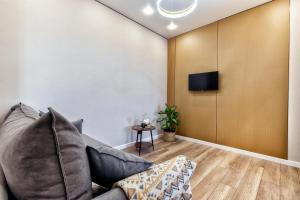 a living room with a couch and a tv on a wall at Уютная евро-двушка возле ботанического сада in Astana