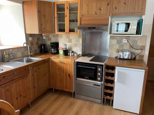 a kitchen with wooden cabinets and a stove top oven at Au cœur du massif jurassien in Les Rousses