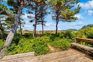 a wooden deck with a bench and trees at Beach Time Getaway in Lincoln City