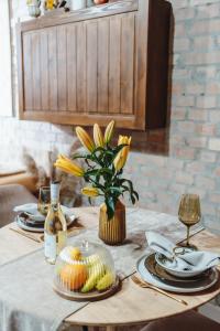 a table with plates and a vase of yellow flowers at História Présház boutique Nagyréde in Gyöngyös +26 photos