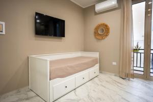 a white bed in a room with a flat screen tv at Experience Napoli Center in Naples