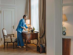 a woman standing next to a desk in a room at Fairmont Hotel Vier Jahreszeiten in Hamburg