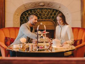 a man and a woman sitting at a table with desserts at Fairmont Hotel Vier Jahreszeiten in Hamburg