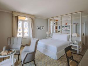 a bedroom with a white bed and a table and chairs at Fairmont Le Montreux Palace in Montreux