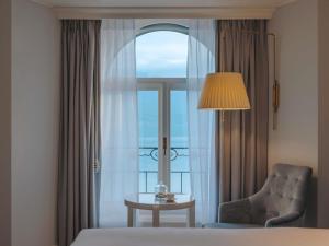 a room with a bed and a chair and a window at Fairmont Le Montreux Palace in Montreux