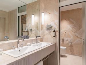 a bathroom with a sink and a toilet and a mirror at Fairmont Le Montreux Palace in Montreux
