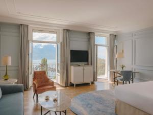 a bedroom with a bed and a living room with a television at Fairmont Le Montreux Palace in Montreux