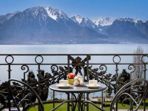 a table with two cups of coffee on a balcony with mountains at Fairmont Le Montreux Palace in Montreux