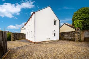 ein weißes Gebäude mit einem Tor und einer Steinmauer in der Unterkunft Two-bed Ground Floor Flat in Caerphilly Town Centre in Caerphilly