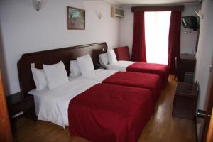 um quarto de hotel com duas camas e um sofá vermelho em Hotel Turismo Miranda em Miranda do Douro