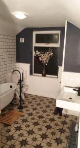 un baño con un jarrón de flores en una ventana en Eton House, en Derby 3 fotos más