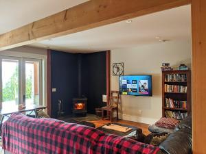 a living room with a couch and a tv at Mountain House of Wonder in Qualicum Beach