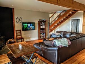 a living room with a leather couch and a tv at Mountain House of Wonder in Qualicum Beach