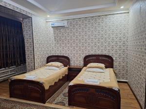 two beds in a room with a wall at Shohruh Hotel in Guliston