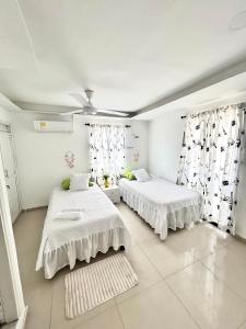 Casa Eme Hostal في كارتاهينا دي اندياس: سريرين في غرفة بجدران بيضاء وستائر