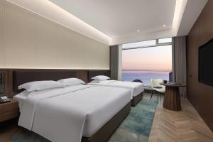 two beds in a hotel room with a large window at Days Hotel by Wyndham Weihai Huoju Eight Street in Weihai +15 photos