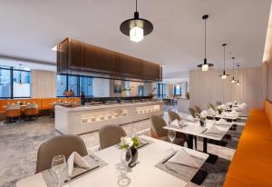 a restaurant with white tables and chairs and a kitchen at Ramada by Wyndham Hangzhou Yuhang in Hangzhou