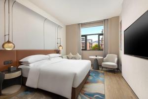 ein Hotelzimmer mit einem großen Bett und einem Fernseher in der Unterkunft Wyndham Garden Changsha University Town in Changsha + 10 Fotos