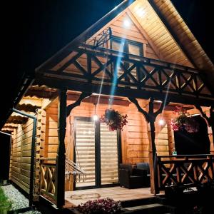 a log cabin with a porch at night at Agroturystyka - TI AMO Nielisz in Nielisz