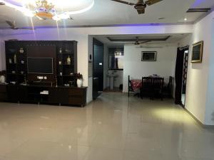 a living room with a television and a dining room at Grand City Retreat 4BHK Balcony Bliss in Manikonda in Hyderabad