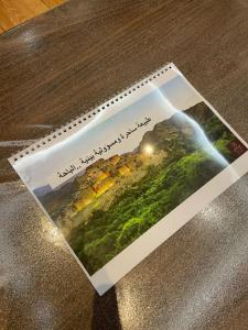 Un libro sobre una mesa con una imagen de una cascada. en شقق ذي كادي المخدومة The Kadi Serviced Apartments, en Al Bahah