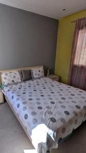 een slaapkamer met een groot bed en een dekbed bij Appartement meublée in Kenitra