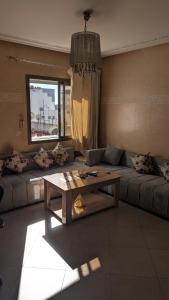 een woonkamer met een bank en een tafel bij Appartement meublée in Kenitra