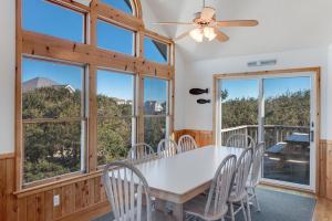 a dining room with a table and chairs and windows at Sea-renity in Corolla