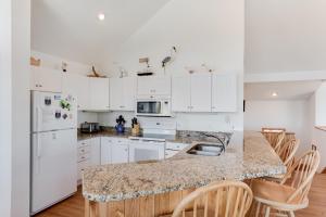 a kitchen with white cabinets and a marble counter top at Sea-renity in Corolla +22 photos