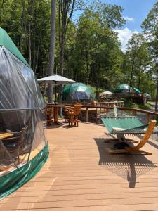 une terrasse en bois avec tables, parasols et bancs dans l'établissement Domes at Catskills, à Swan Lake