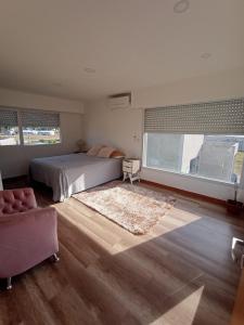 ein Schlafzimmer mit einem Bett, einem Stuhl und einem Teppich in der Unterkunft Casa Grande para 7 personas in Balneario Claromecó