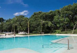 ein großer blauer Pool mit Bäumen im Hintergrund in der Unterkunft Departamento Residencial erca de Centros Comerciales in Cancún