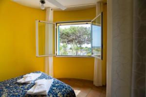 Habitación amarilla con cama y ventana en Villa Saba, en Lampedusa