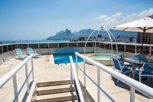 a balcony with a pool and chairs and an umbrella at Atlantis Copacabana Hotel in Rio de Janeiro