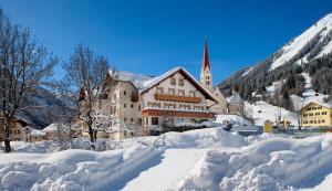 a large building covered in snow with a church at Gasthof Bären in Holzgau
