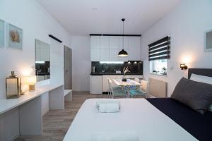 a bedroom with a large white bed and a kitchen at Studioapartment Black & White in Velika Gorica