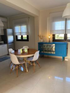 a dining room with a wooden table and white chairs at ALKYONI HOUSE IN AFYTOS in Afitos