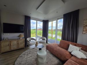 a living room with a couch and a large window at Waddenlodge Deluxe in Harlingen