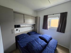 a bedroom with a bed with blue sheets and a window at Waddenlodge Deluxe in Harlingen