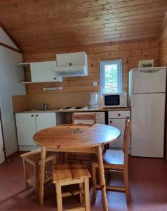 a small kitchen with a table and a refrigerator at Chalet nature et lac dans parc résidentiel de loisirs in Lissac-sur-Couze