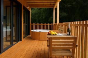 a wooden deck with a hot tub and a bottle of wine at Cabañas Compostela - Cabaña A Fervenza in Santiago de Compostela +2 photos
