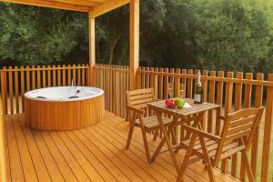 a deck with a tub and a table and chairs at Cabañas Compostela - Cabaña A Fervenza in Santiago de Compostela