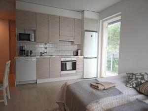 a kitchen with white appliances and a bed in a room at Kampuksen Hertta in Pori